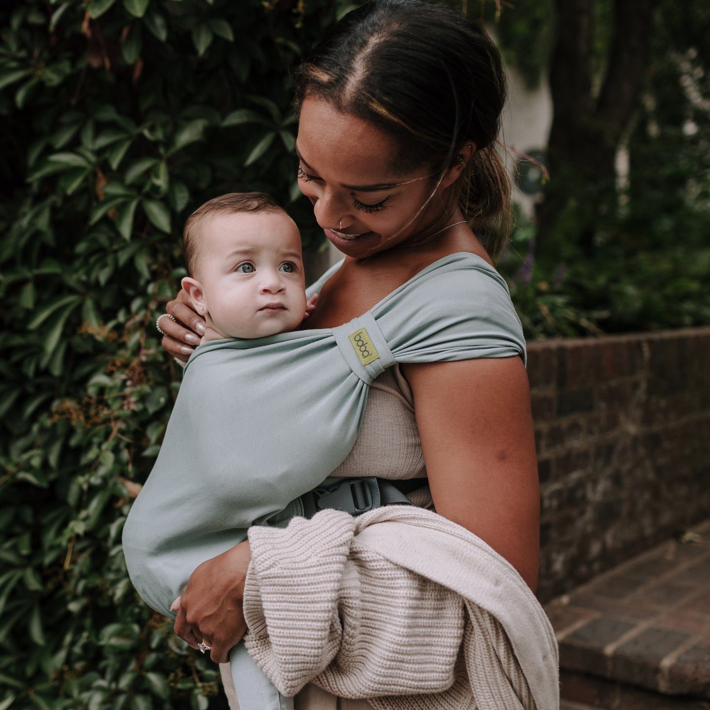 Woman holding a baby in a sling outdoors