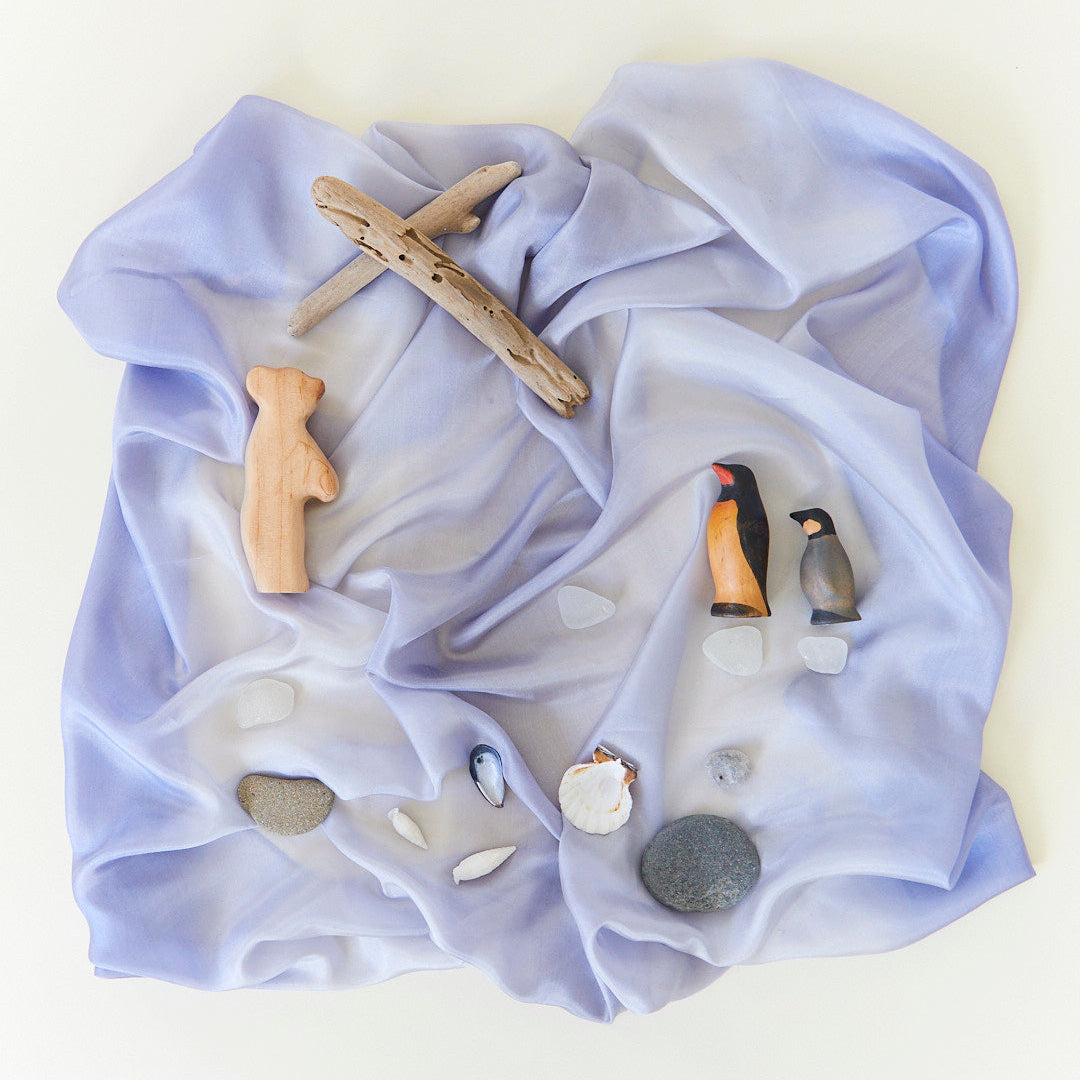 Light stone coloured fabric with wooden and nature items on a white background