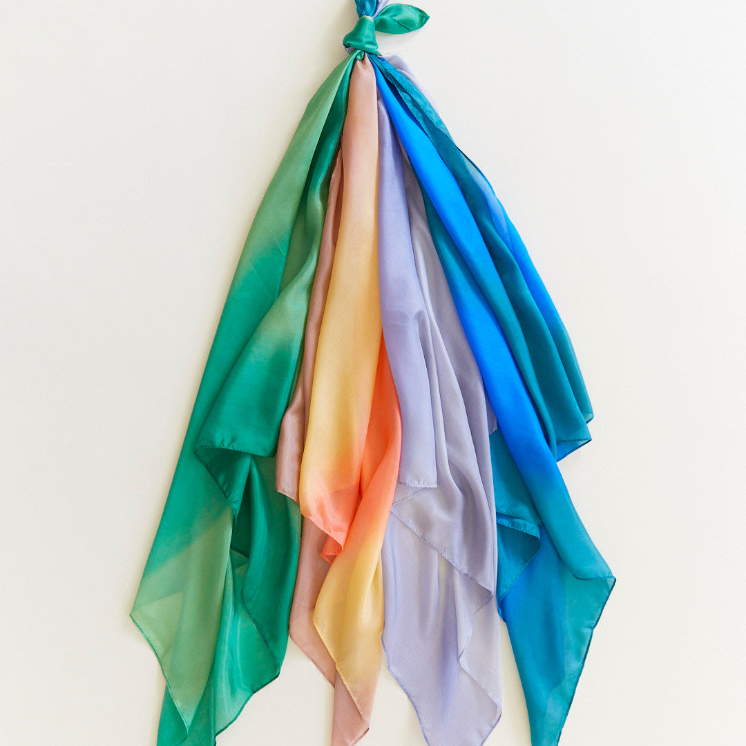 Colorful scarf with gradient hues of green, blue, orange, and pink draped over a white background.