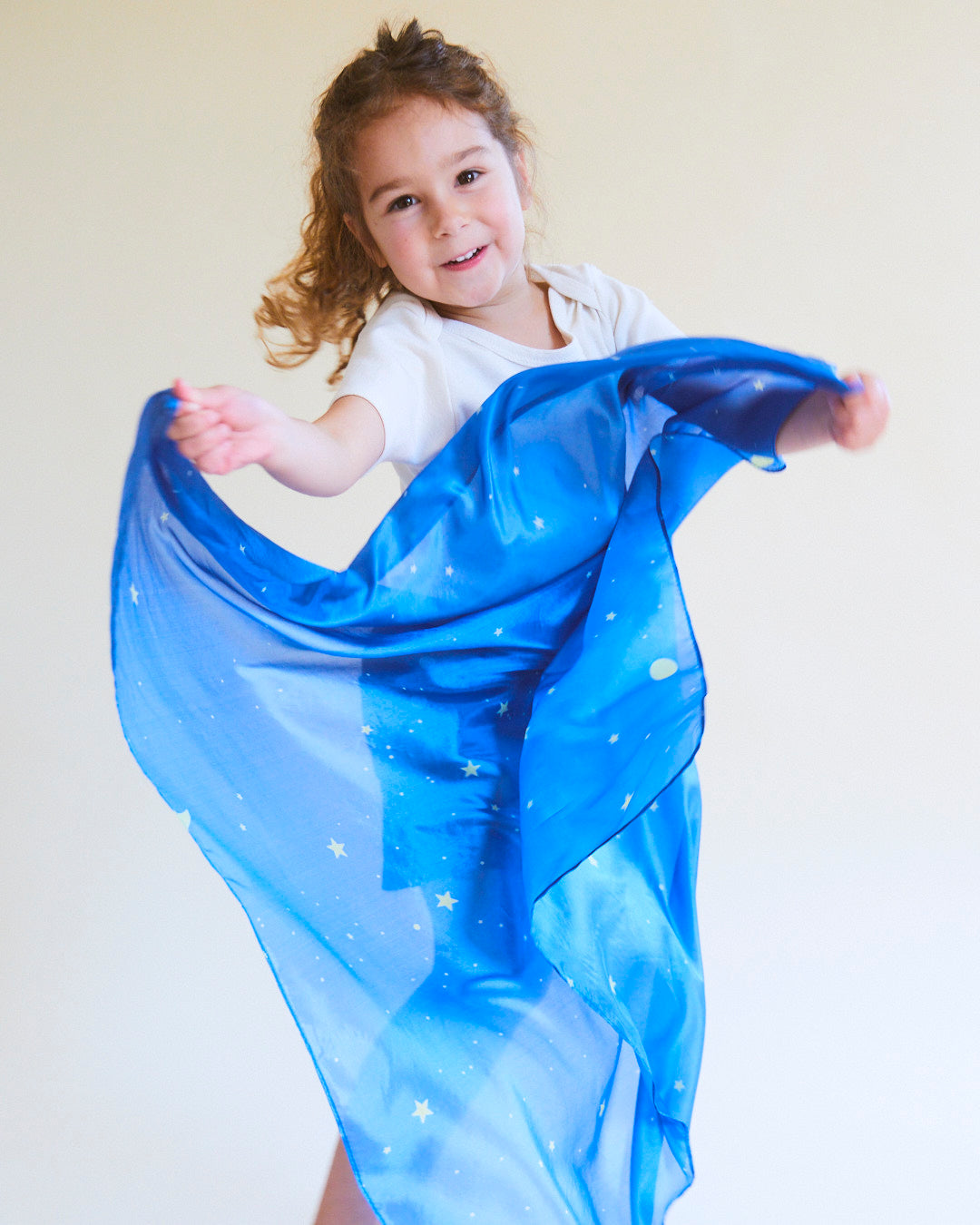 Child holding a blue scarf with star patterns against a plain background