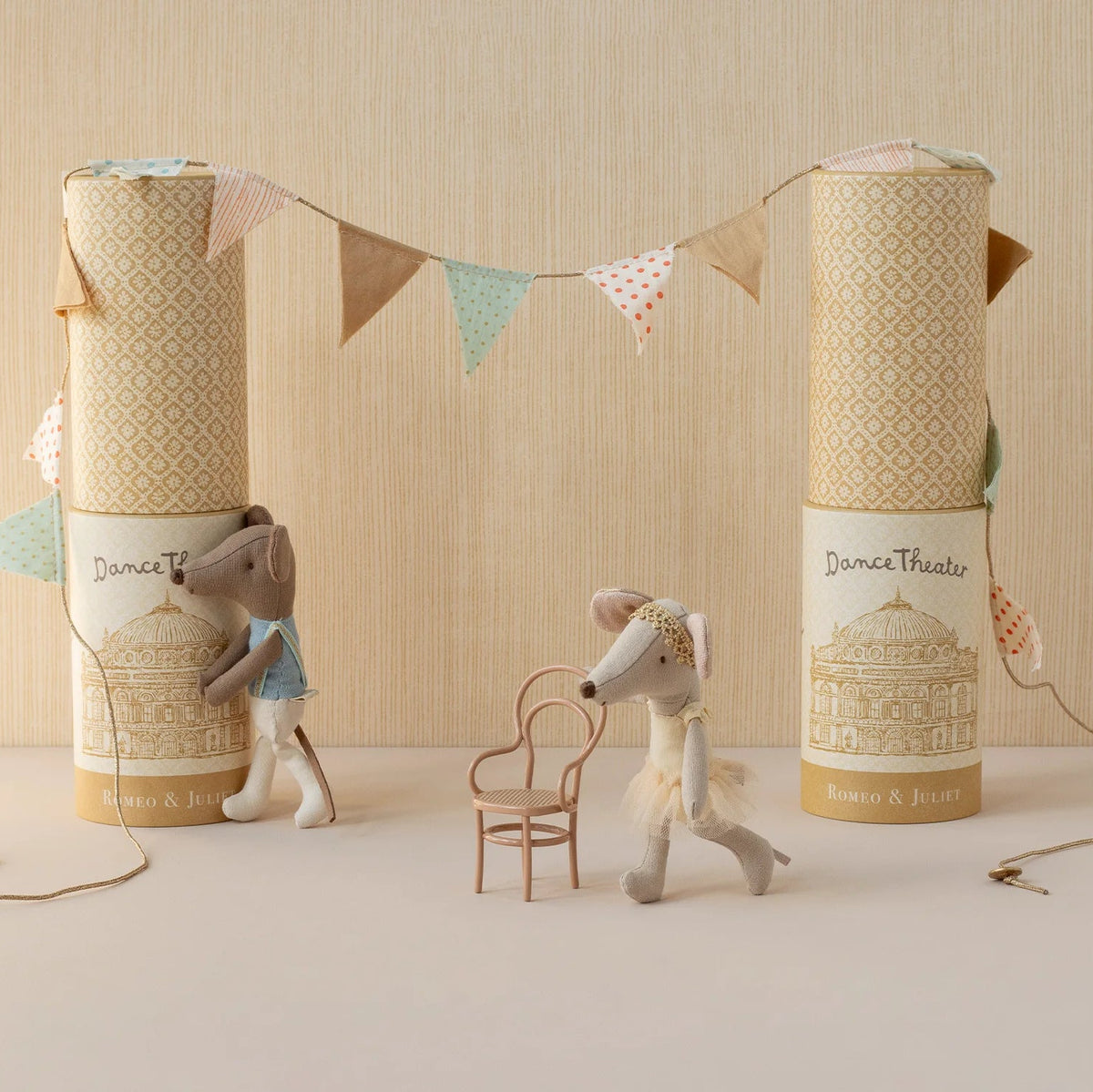 Two stuffed animal toys with decorative boxes and a banner on a neutral background