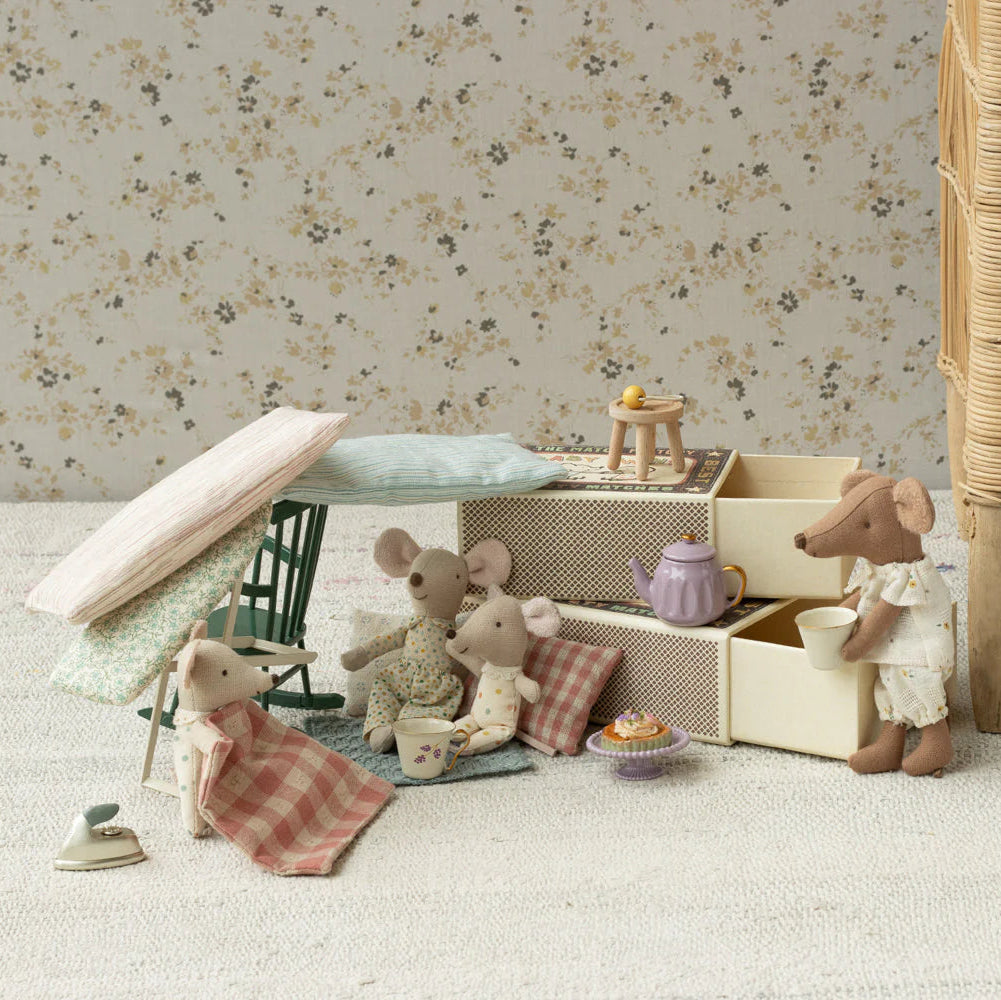 Miniature scene with toy mice and furniture against a floral wallpapered wall.
