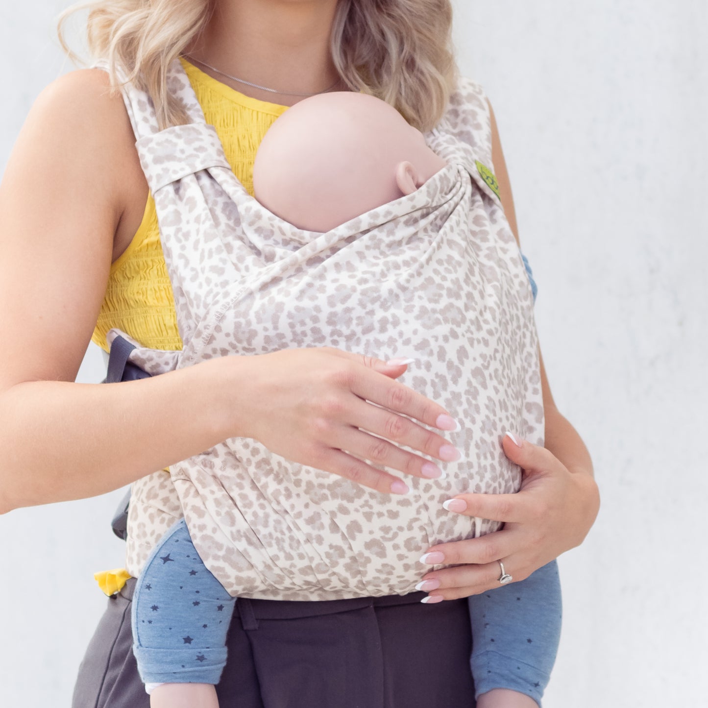 Person wearing a leopard print baby carrier with a plain background