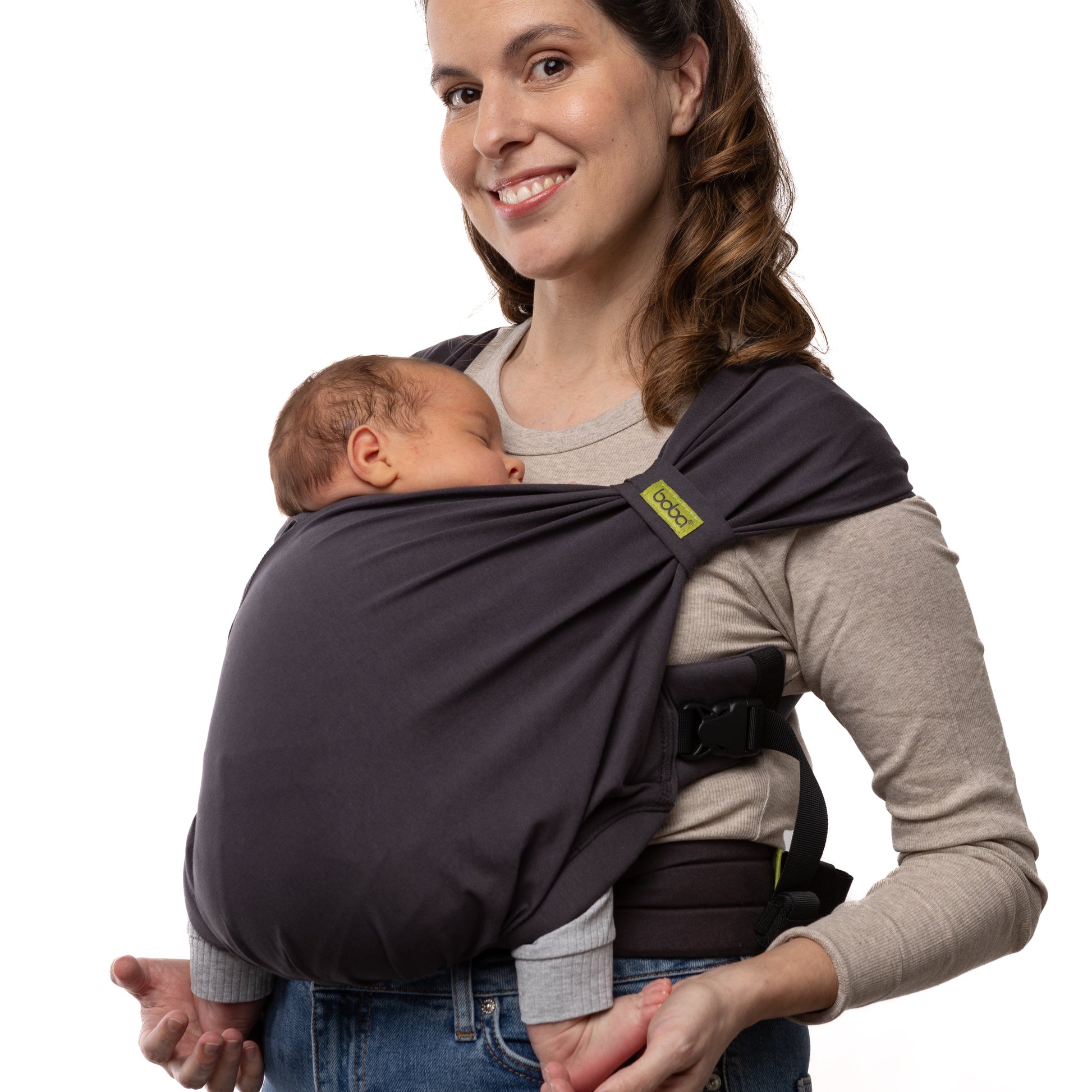 Woman holding a baby in a dark gray baby carrier against a white background