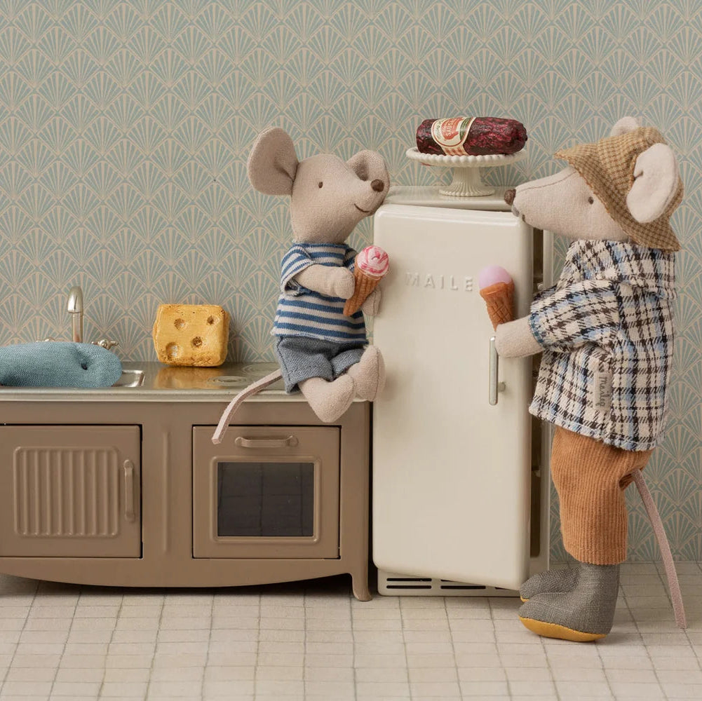 Two toy mice in a kitchen setting with a refrigerator and sink.