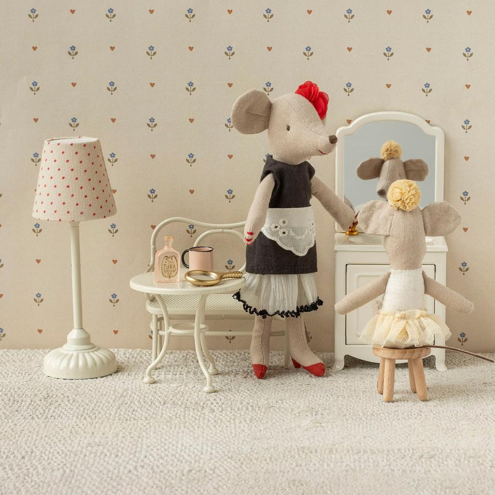 Two toy mice in a room with a lamp, table, and mirror.
