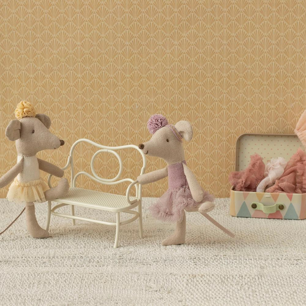 Two toy mice with a chair and box on a textured surface with patterned wall background