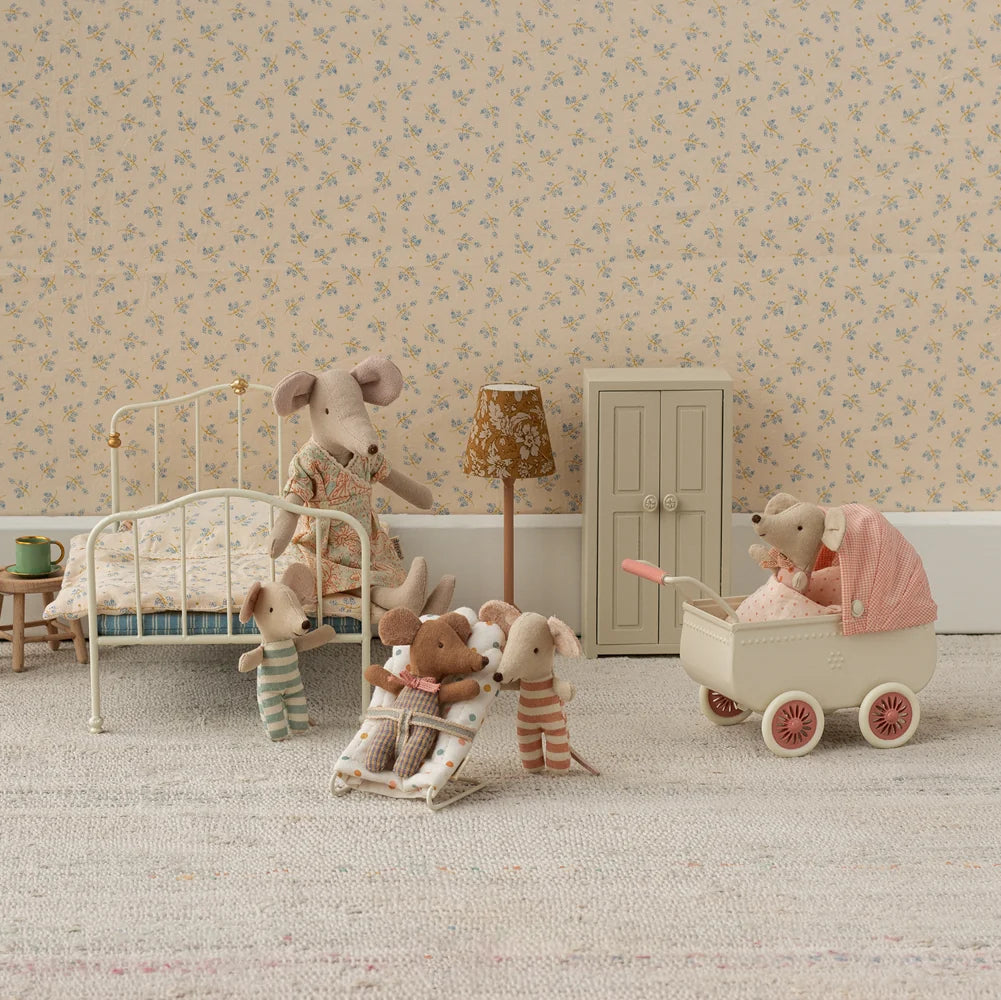 Miniature bedroom scene with toy mice and furniture against a floral wallpapered wall.
